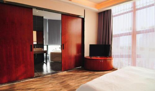 a bedroom with a bed and a bathroom with a television at Hangzhou Berman Hotel in Hangzhou