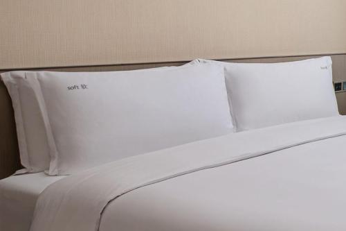 a bed with white sheets and pillows on it at Holiday Inn Chengdu Century City-EastTower in Chengdu