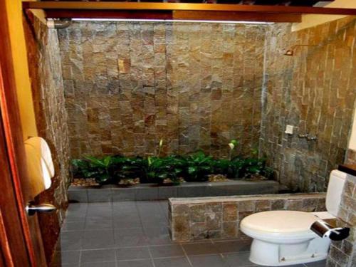 ein Badezimmer mit Toilette und Pflanzen in der Dusche in der Unterkunft Kalibaru Cottages in Banyuwangi