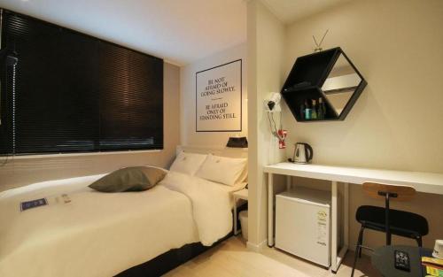 a bedroom with a bed and a desk and a window at Hotel Yam ANDONG in Andong