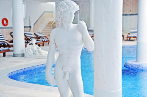 a white statue of a man standing next to a pool at Grand Hotel Palladium Santa Eulalia del Río in Santa Eularia des Riu