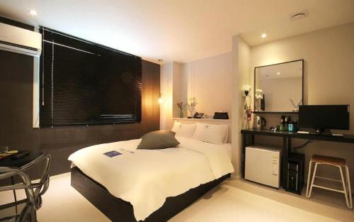 a bedroom with a bed and a desk and a television at Hotel Yam ANDONG in Andong