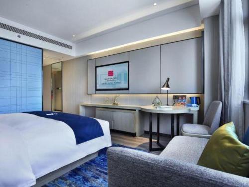 a bedroom with a bed and a desk and a couch at Echarm Hotel Guilin North High Speed Railway Station in Guilin