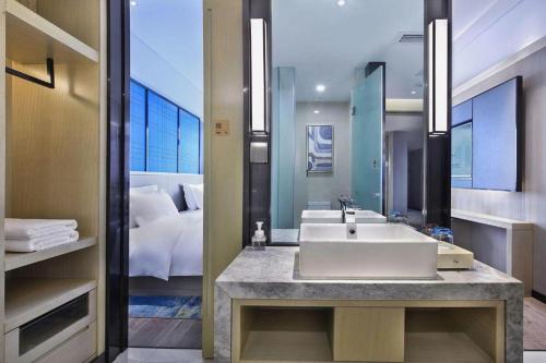 a bathroom with a white sink and a bed at Echarm Hotel Guilin North High Speed Railway Station in Guilin