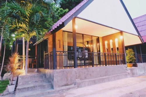 a building with stairs and palm trees in front of it at Rim Kaeng resort in Phetchaburi