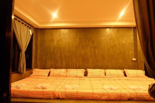 a large bed in a bedroom with a wooden wall at Rim Kaeng resort in Phetchaburi