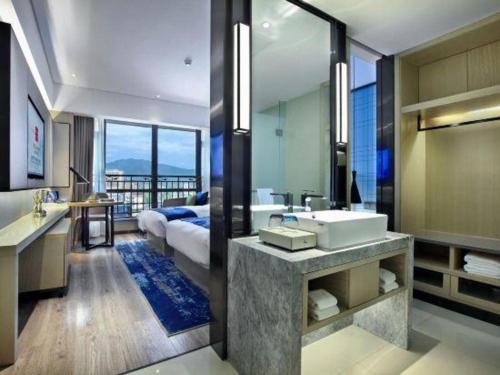 a bathroom with a sink and a bed and a mirror at Echarm Hotel Guilin North High Speed Railway Station in Guilin