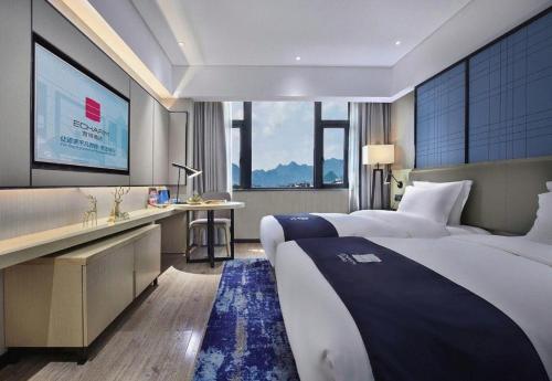 a hotel room with a large bed and a desk at Echarm Hotel Guilin North High Speed Railway Station in Guilin