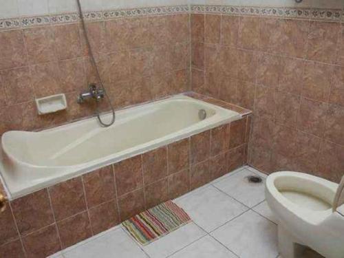 a bathroom with a bath tub and a toilet at Larisae Setia Kawan Hotel in Solo