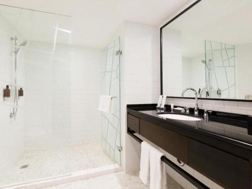 a bathroom with a sink and a shower with a mirror at Beijing New World Center Tongpai Hotel in Beijing