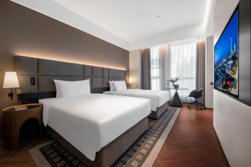 a hotel room with two beds and a flat screen tv at Taiyuan Jinyang Lake Intercity Hotel in Taiyuan