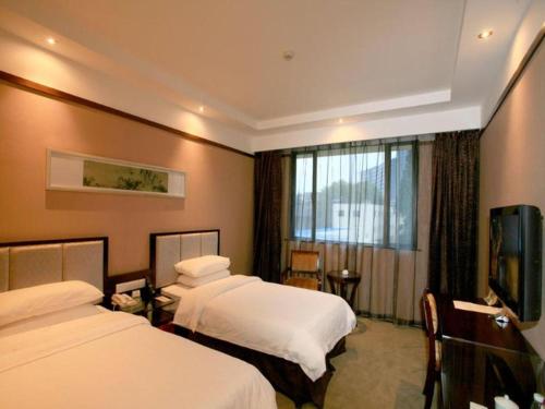a hotel room with two beds and a flat screen tv at Jin Jiang Nanjing Hotel in Nanjing