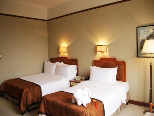 a hotel room with two beds with white sheets at Jin Jiang Nanjing Hotel in Nanjing