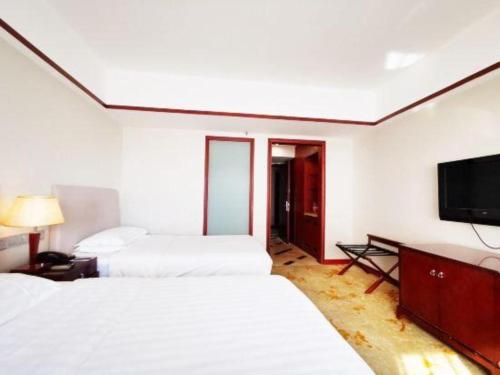 a hotel room with two beds and a flat screen tv at Starmoon Hotel in Beijing