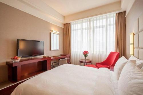 a hotel room with a bed and a desk and a television at Best Western Plus Fuzhou Fortune Hotel in Fuzhou