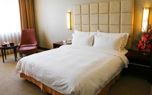 a hotel room with a large white bed and a chair at Best Western Plus Fuzhou Fortune Hotel in Fuzhou