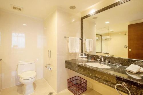 a bathroom with a toilet and a sink and a mirror at Best Western Plus Fuzhou Fortune Hotel in Fuzhou