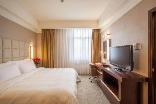 a hotel room with a bed and a desk with a television at Best Western Plus Fuzhou Fortune Hotel in Fuzhou
