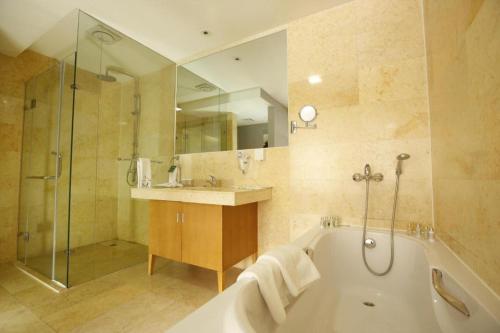a bathroom with a tub and a sink and a shower at The Corporate Hotel and Convention Centre in Ulaanbaatar
