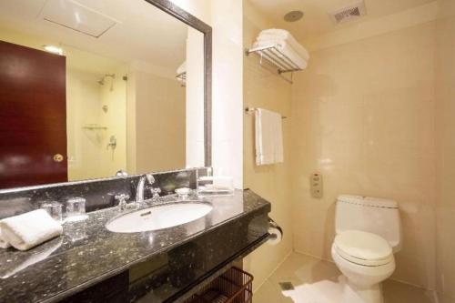 a bathroom with a sink and a toilet and a mirror at Best Western Plus Fuzhou Fortune Hotel in Fuzhou