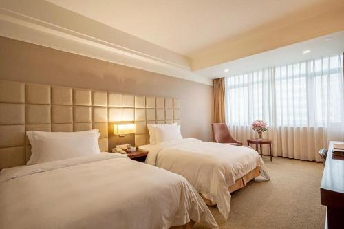 a hotel room with two beds and a window at Best Western Plus Fuzhou Fortune Hotel in Fuzhou