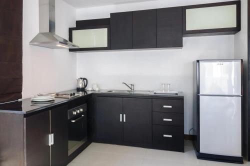 a kitchen with black cabinets and a refrigerator at Ocean Breeze Residence in Khao Lak