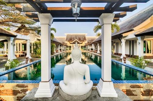 aitating buddha statue in front of a pool at a resort at Ocean Breeze Residence in Khao Lak