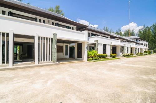 a row of white buildings with a parking lot at Ocean Breeze Residence in Khao Lak