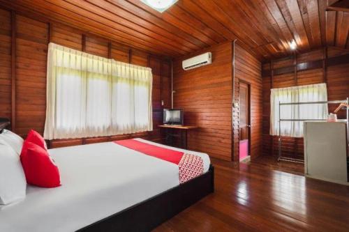 une chambre avec un lit blanc et des murs en bois dans l'établissement OYO 1143 Phet Luran Thai Resort Kohchang, à Ko Chang