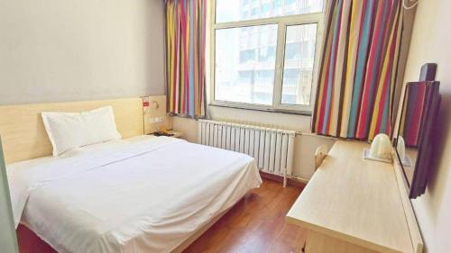 a bedroom with a white bed and a window at 7 Days Inn Hohhot Hailiang Xinhua Square Metro Station in Hohhot
