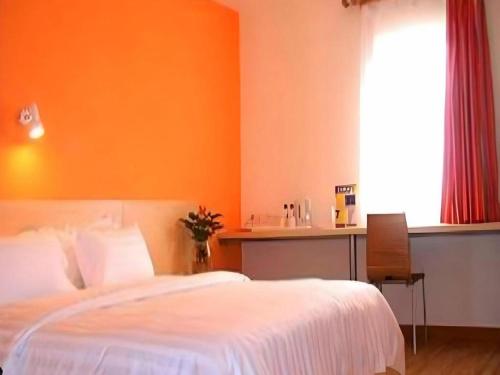 a bedroom with a bed and a desk and a window at 7 Days Inn Hohhot Hailiang Xinhua Square Metro Station in Hohhot