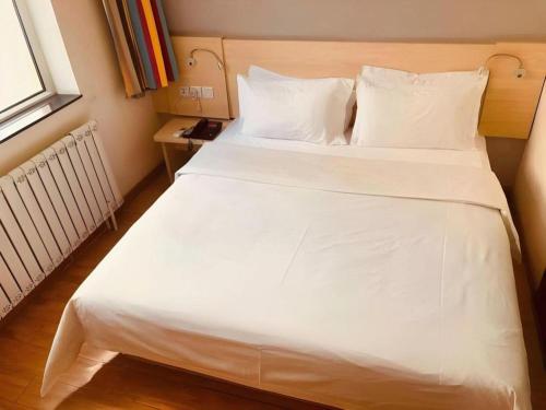 a large white bed in a room with a window at 7 Days Inn Hohhot Hailiang Xinhua Square Metro Station in Hohhot