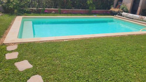 a swimming pool in a yard with green grass at Chambre d'hôte dans une maison cosy in Saint-Martin-de-Crau
