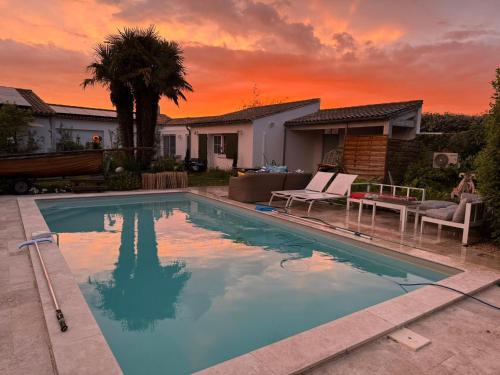 une piscine avec un coucher de soleil en arrière-plan dans l'établissement Escapades Océanes Ile de Ré La Rochelle, à Sainte-Marie de Ré