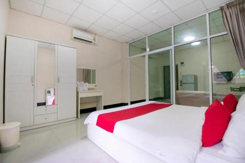 a bedroom with a large white bed with red pillows at OYO 75390 Sunee Place Hotel in Rayong