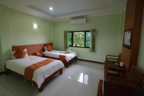 a bedroom with two beds and a television in it at CK Hills Hotel in Mae Sot