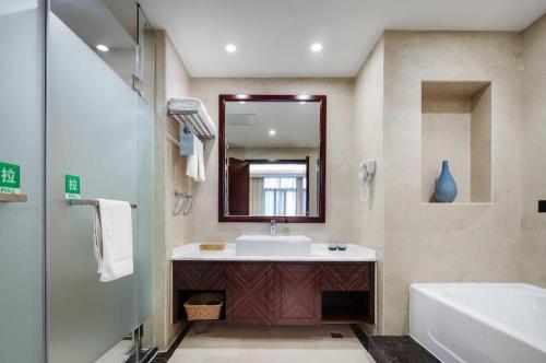 Un baño con lavabo, bañera y espejo. en ibis Styles Nanjing Qilin Gate Hotel, en Qilinmen