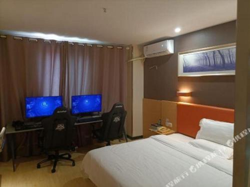 a bedroom with two beds and a desk with two monitors at 7 Days Premium·Xiamen Airport Xianglu in Xiamen
