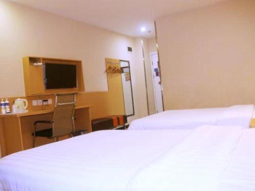 a hotel room with two beds and a desk and a television at 7 Days Premium·Xiamen Airport Xianglu in Xiamen