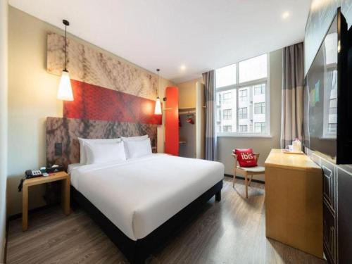 a hotel room with a large white bed and a desk at Ibis Xian Hi-Tech Zone No.7 Keji Rd Hotel in Xi'an
