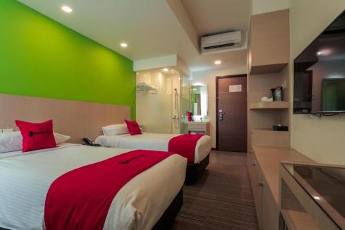 a hotel room with two beds and a green wall at RedDoorz Premium @ Balestier in Singapore