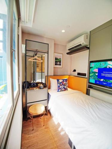 a bedroom with two beds and a flat screen tv at Hotel Soloha @ Chinatown in Singapore