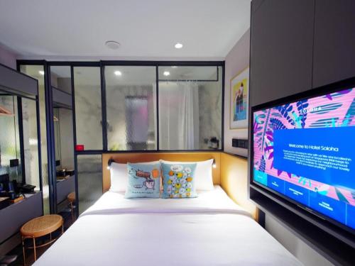 a bedroom with a bed and a flat screen tv at Hotel Soloha @ Chinatown in Singapore