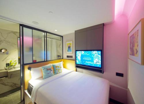 a bedroom with a white bed and a tv at Hotel Soloha @ Chinatown in Singapore