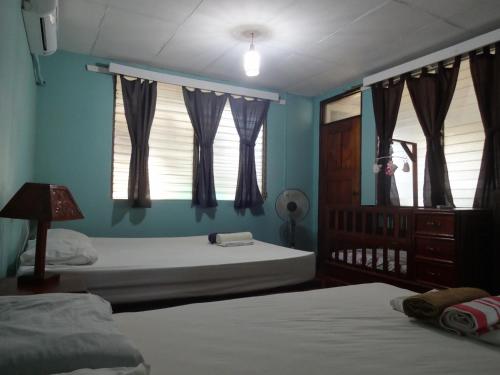a bedroom with two beds and a window with curtains at Hostal Harvest House in León
