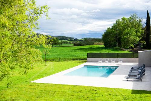 a swimming pool with lounge chairs in a yard at Casa Rural Mas Homs in Parets de Dalt