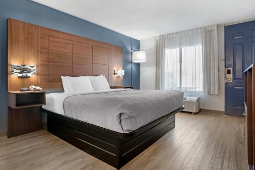 a bedroom with a large bed and a blue wall at Quality Inn & Suites near Lake Eufaula in Eufaula