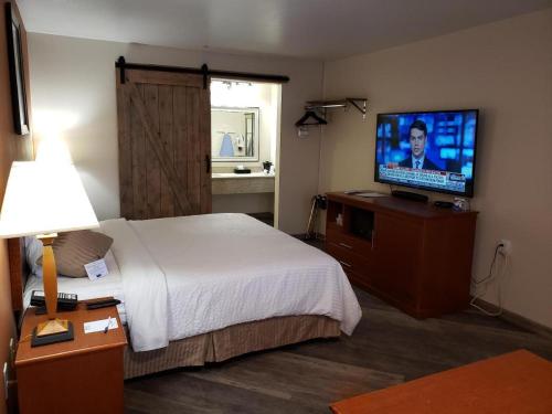 a hotel room with a bed and a flat screen tv at Airport Inn in Boise