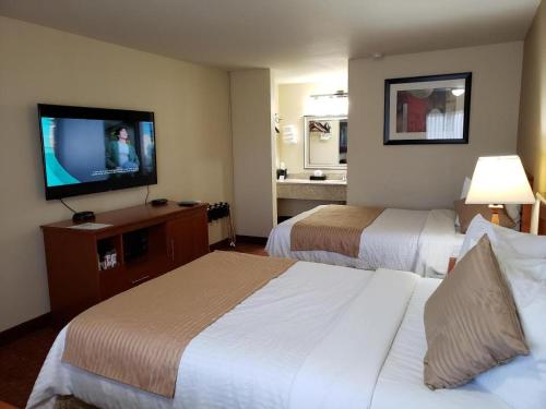 a hotel room with two beds and a flat screen tv at Airport Inn in Boise