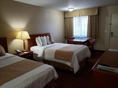 a hotel room with two beds and a desk at Airport Inn in Boise